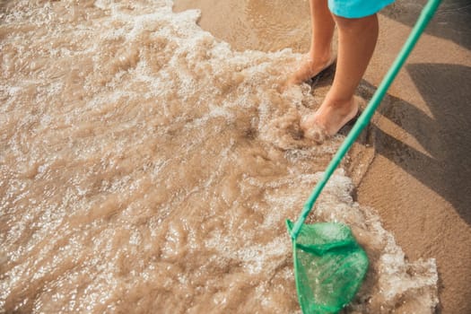 Unrecognisable little boy playing at the water's edge at the beach.