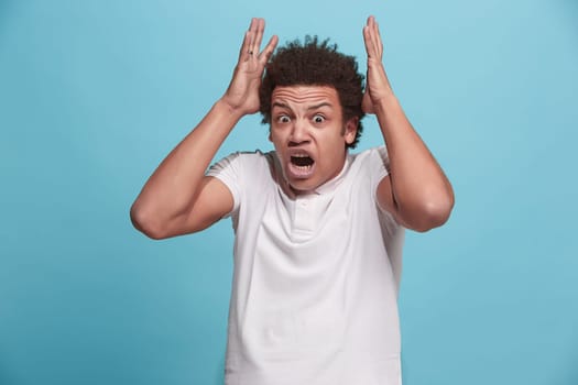 Screaming, hate, rage. Crying emotional angry man screaming on blue studio background. Emotional, young face. male half-length portrait. Human emotions, facial expression concept. Trendy colors