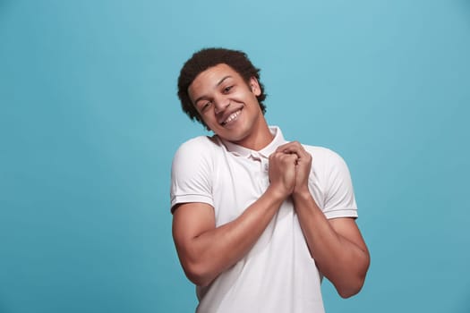 Delight. Beautiful male half-length front portrait isolated on blue studio backgroud. Young, emotional, smiling, surprised man standing. Human emotions, facial expression concept. Trendy colors