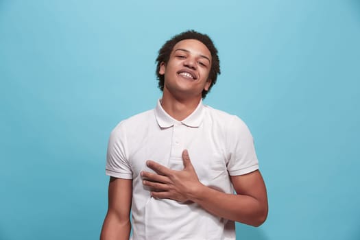 Happy business man standing and smiling isolated on blue studio background. Beautiful male half-length portrait. Young emotional man. The human emotions, facial expression concept. Front view.