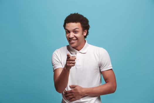 I choose you and order. The smiling business man point you, want you, half length closeup portrait on blue studio background. The human emotions, facial expression concept. Front view. Trendy colors