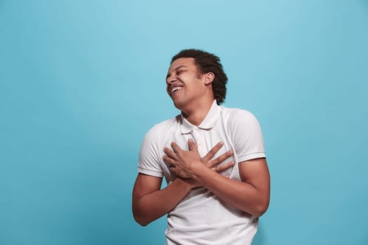 Happy business man standing and smiling isolated on blue studio background. Beautiful male half-length portrait. Young emotional man. The human emotions, facial expression concept. Front view.