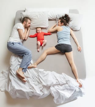 Top view of happy funny family with one newborn child in bedroom. Enjoying being together. Happy family in bed. Top view. Emotions concept. Morning after sleep. Family lifestyle. happy parents concept