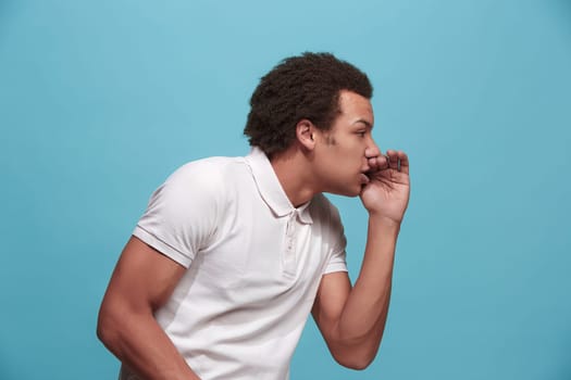 Do not miss. Young casual man shouting. Shout. Crying emotional man screaming on blue studio background. male half-length portrait. Human emotions, facial expression concept. Trendy colors