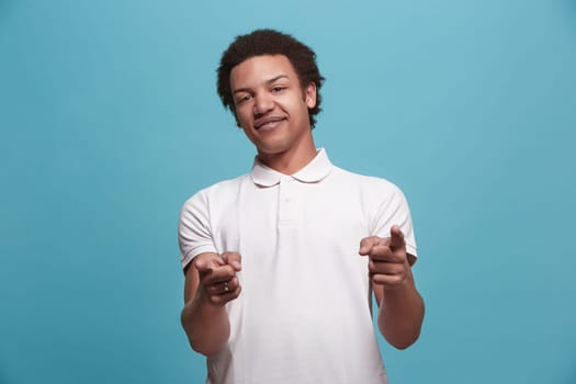 I choose you and order. The smiling business man point you, want you, half length closeup portrait on blue studio background. The human emotions, facial expression concept. Front view. Trendy colors
