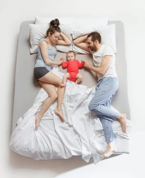 Top view of happy funny family with one newborn child in bedroom. Enjoying being together. Happy family in bed. Top view. Emotions concept. Morning after sleep. Family lifestyle. happy parents concept