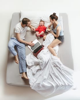 Top view of happy funny family with one newborn child in bedroom. Enjoying being together. Happy family in bed. Top view. Emotions concept. Morning after sleep. Family lifestyle. happy parents concept