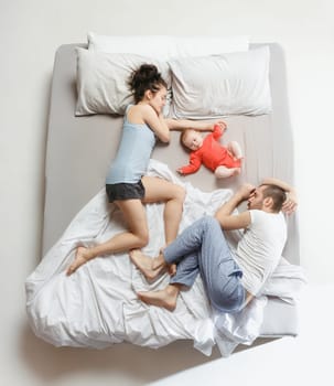Top view of happy funny family with one newborn child in bedroom. Enjoying being together. Happy family in bed. Top view. Emotions concept. Morning after sleep. Family lifestyle. happy parents concept