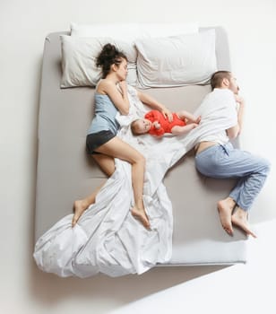 Top view of happy funny family with one newborn child in bedroom. Enjoying being together. Happy family in bed. Top view. Emotions concept. Morning after sleep. Family lifestyle. happy parents concept