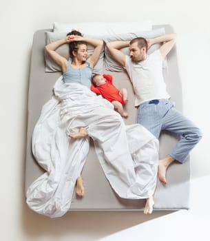 Top view of happy funny family with one newborn child in bedroom. Enjoying being together. Happy family in bed. Top view. Emotions concept. Morning after sleep. Family lifestyle. happy parents concept