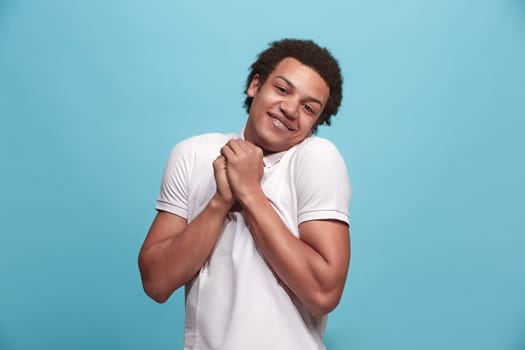 Delight. Beautiful male half-length front portrait isolated on blue studio backgroud. Young, emotional, smiling, surprised man standing. Human emotions, facial expression concept. Trendy colors