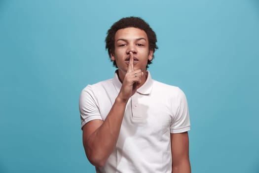 Secret, gossip concept. Young man whispering a secret behind his hand. Businessman isolated on trendy blue studio background. Young emotional man. Human emotions, facial expression concept.