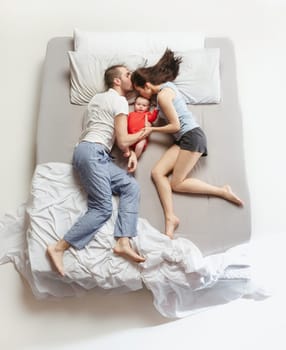 Top view of happy funny family with one newborn child in bedroom. Enjoying being together. Happy family in bed. Top view. Emotions concept. Morning after sleep. Family lifestyle. happy parents concept