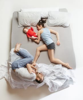 Top view of happy funny family with one newborn child in bedroom. Enjoying being together. Happy family in bed. Top view. Emotions concept. Morning after sleep. Family lifestyle. happy parents concept