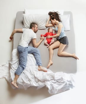 Top view of happy funny family with one newborn child in bedroom. Enjoying being together. Happy family in bed. Top view. Emotions concept. Morning after sleep. Family lifestyle. happy parents concept