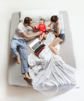 Top view of happy funny family with one newborn child in bedroom. Enjoying being together. Happy family in bed. Top view. Emotions concept. Morning after sleep. Family lifestyle. happy parents concept