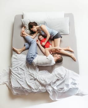 Top view of happy funny family with one newborn child in bedroom. Enjoying being together. Happy family in bed. Top view. Emotions concept. Morning after sleep. Family lifestyle. happy parents concept