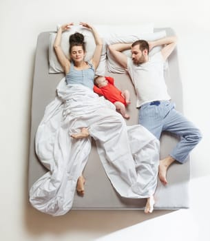 Top view of happy funny family with one newborn child in bedroom. Enjoying being together. Happy family in bed. Top view. Emotions concept. Morning after sleep. Family lifestyle. happy parents concept