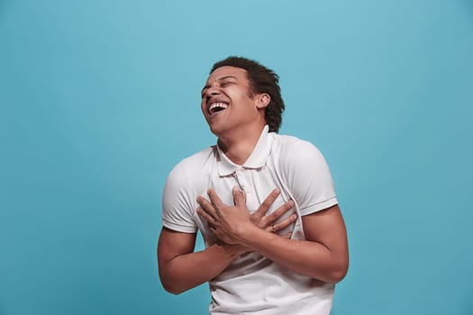 Happy business man standing and smiling isolated on blue studio background. Beautiful male half-length portrait. Young emotional man. The human emotions, facial expression concept. Front view.