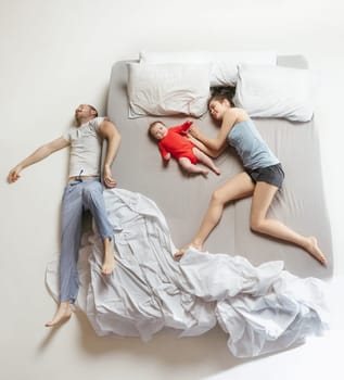 Top view of happy funny family with one newborn child in bedroom. Enjoying being together. Happy family in bed. Top view. Emotions concept. Morning after sleep. Family lifestyle. happy parents concept
