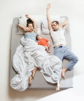Top view of happy funny family with one newborn child in bedroom. Enjoying being together. Happy family in bed. Top view. Emotions concept. Morning after sleep. Family lifestyle. happy parents concept