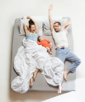 Top view of happy funny family with one newborn child in bedroom. Enjoying being together. Happy family in bed. Top view. Emotions concept. Morning after sleep. Family lifestyle. happy parents concept