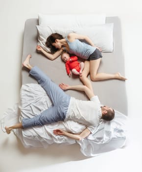 Top view of happy funny family with one newborn child in bedroom. Enjoying being together. Happy family in bed. Top view. Emotions concept. Morning after sleep. Family lifestyle. happy parents concept