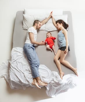 Top view of happy funny family with one newborn child in bedroom. Enjoying being together. Happy family in bed. Top view. Emotions concept. Morning after sleep. Family lifestyle. happy parents concept
