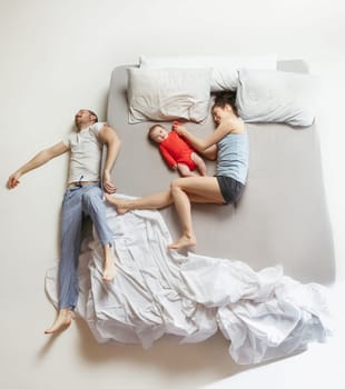 Top view of happy funny family with one newborn child in bedroom. Enjoying being together. Happy family in bed. Top view. Emotions concept. Morning after sleep. Family lifestyle. happy parents concept