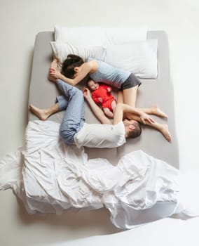 Top view of happy funny family with one newborn child in bedroom. Enjoying being together. Happy family in bed. Top view. Emotions concept. Morning after sleep. Family lifestyle. happy parents concept
