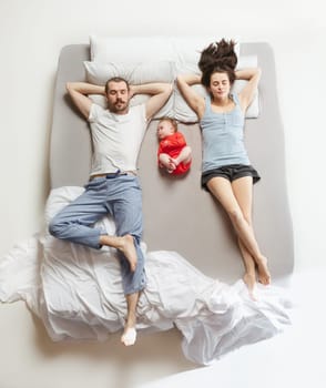Top view of happy funny family with one newborn child in bedroom. Enjoying being together. Happy family in bed. Top view. Emotions concept. Morning after sleep. Family lifestyle. happy parents concept