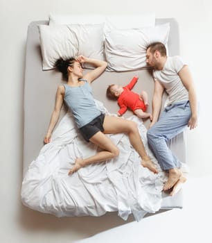 Top view of happy funny family with one newborn child in bedroom. Enjoying being together. Happy family in bed. Top view. Emotions concept. Morning after sleep. Family lifestyle. happy parents concept