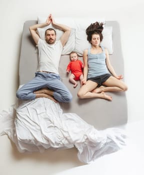Top view of happy funny family with one newborn child in bedroom. Enjoying being together. Happy family in bed. Top view. Emotions concept. Morning after sleep. Family lifestyle. happy parents concept
