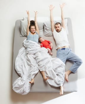 Top view of happy funny family with one newborn child in bedroom. Enjoying being together. Happy family in bed. Top view. Emotions concept. Morning after sleep. Family lifestyle. happy parents concept