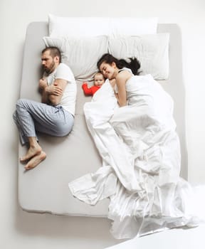 Top view of happy funny family with one newborn child in bedroom. Enjoying being together. Happy family in bed. Top view. Emotions concept. Morning after sleep. Family lifestyle. happy parents concept