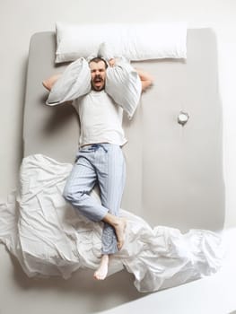 Top view photo of young man sleeping in a big white bed. Emotions concept. Morning after sleep. Happy man on the bed. alarm clock and unwillingness to wake up