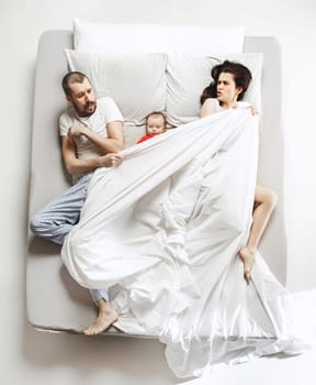 Top view of happy funny family with one newborn child in bedroom. Enjoying being together. Happy family in bed. Top view. Emotions concept. Morning after sleep. Family lifestyle. happy parents concept
