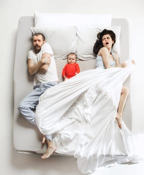 Top view of happy funny family with one newborn child in bedroom. Enjoying being together. Happy family in bed. Top view. Emotions concept. Morning after sleep. Family lifestyle. happy parents concept