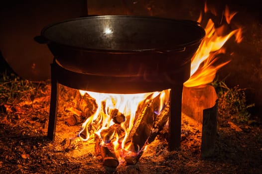 Camping fire and kettle with frying fish