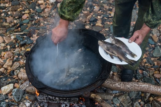delicious fresh-soup from fish cooked in the metal pot at outdoors