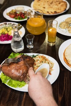 Man eats tasty dish of pork shank, closeup photo