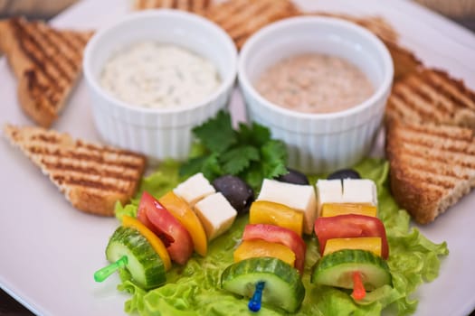 Tasty snacks: roasted toast with cheese vegetables and olive on the stick. Served with two kind of sauce