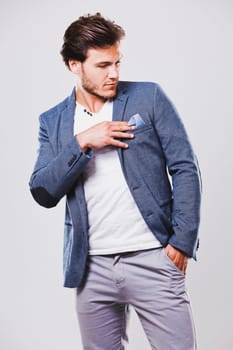 Fashion portrait of a handsome man with trendy hairstyle in a stylish jacket on light background