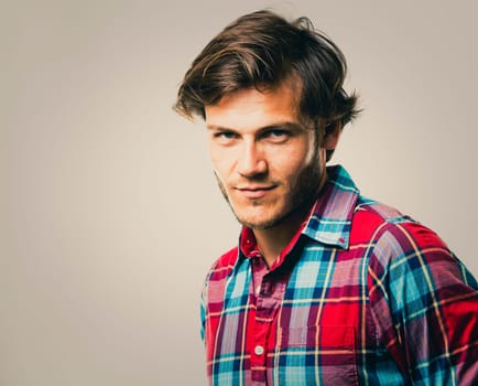 Fashion portrait of a handsome man with trendy hairstyle in a stylish shirt on light green background