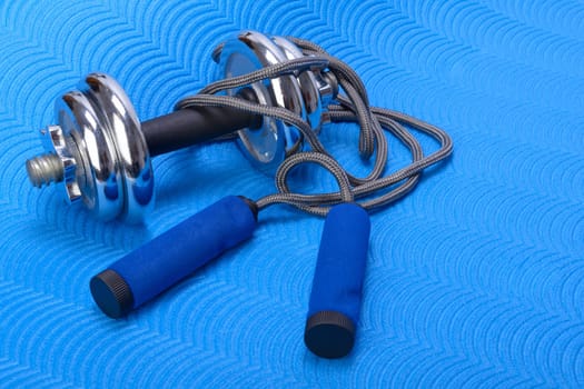 Sports fitness accessories on blue training mat. Frame, healthy.
