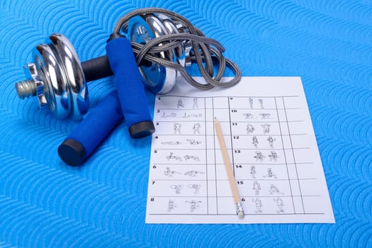 Sports fitness accessories on blue training mat. Table of gymnastic exercises with white space.