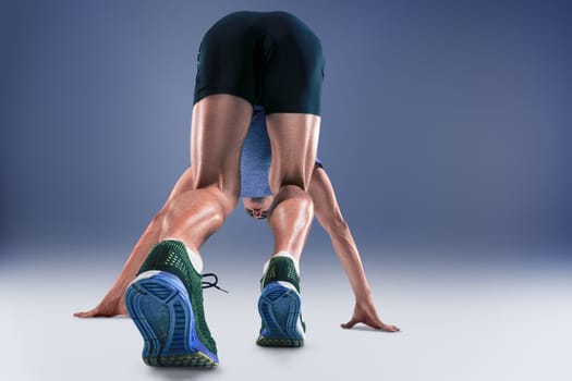 The studio shot of high jump athlete is in action on blue background