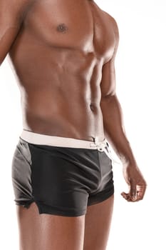Fit young man with beautiful torso, isolated on white background. The naked torso of African American man posing at studio. The muscular body, fitness, sports, healthy lifestyle and bodybuilder concept.