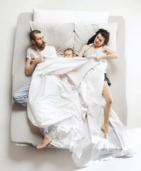Top view of happy funny family with one newborn child in bedroom. Enjoying being together. Happy family in bed. Top view. Emotions concept. Morning after sleep. Family lifestyle. happy parents concept