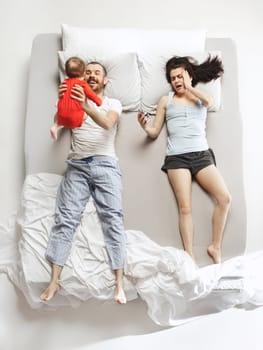 Top view of happy funny family with one newborn child in bedroom. Enjoying being together. Happy family in bed. Top view. Emotions concept. Morning after sleep. Family lifestyle. happy parents concept
